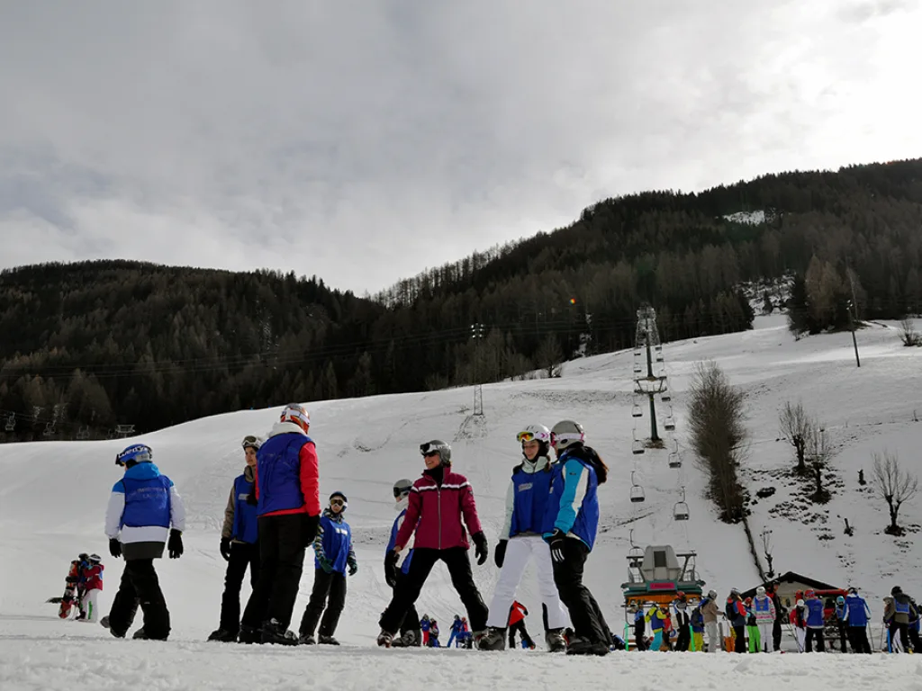 Gruppe sammelt sich am Hangfuß vor dem bewaldeten Berg.